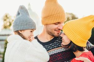 drie gezinsleden staan dicht bij elkaar, kijken met ogen vol liefde en geluk, genieten van fijne momenten van samen zijn, omhelzen elkaar. familie, geluk, ontspanningsconcept foto