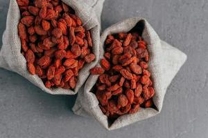 droge superfood goji-bessen voor gezond eten in twee jutezakken geïsoleerd over grijze achtergrond. voedingssupplement. rode wolfsbessen in zakjes foto