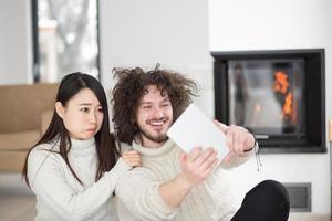 multi-etnisch paar met behulp van tabletcomputer voor open haard foto