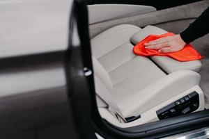 gezichtsloze man reinigt auto-interieur gebruikt doek om lederen stoel af te vegen. selectieve aandacht. auto detailing service. vervoer zorgconcept foto