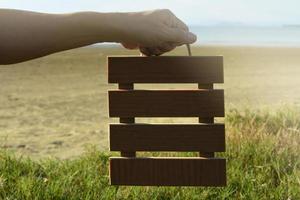 handen met houten frame met onscherpe achtergrond van groen gras en oceaan. foto