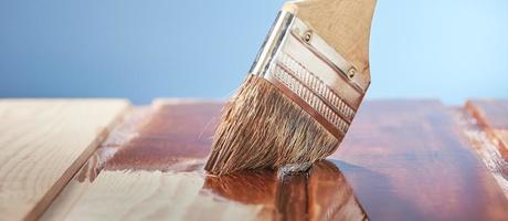 houten vloer schilderen met beschermende vernis op een blauwe achtergrond. foto