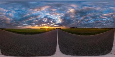 volledig bolvormig naadloos panorama 360 graden hoekzicht op asfaltweg zonder verkeer tussen velden in de avond voor zonsondergang met bewolkte hemel. 360 panorama in equirectangular projectie, vr ar inhoud foto