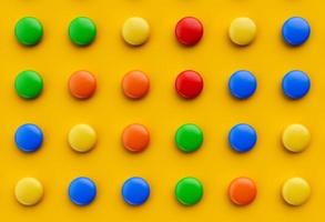 kleurrijke chocolade snoep pillen geïsoleerd op oranje gele achtergrond. bovenaanzicht 3d illustratie foto
