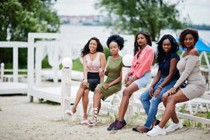 groep van vijf Afro-Amerikaanse meisjes die ontspannen in een prachtige cabana aan het zwembad naast een luxeresort. foto