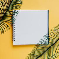 plat leggen van minimale werkruimte blanco notebook met groene plant op gele achtergrond, lente en zomer concept foto