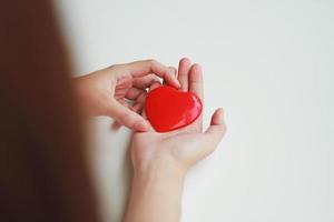 een vrouw met een rood hart op haar handpalm met een witte achtergrond. donatie idee foto