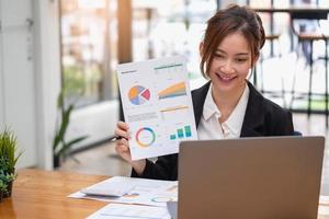 marketing, financieel, boekhouding, planning, zakenvrouwen analyseren bedrijfsresultaten en winst met grafiekstatistieken. gebruik een laptop en een rekenmachine om het saldo van het bedrijf te berekenen. foto