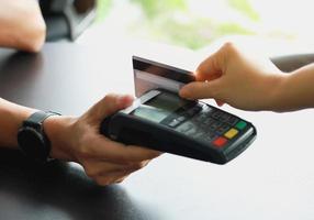 man die een creditcard-veegmachine gebruikt om producten in de winkel aan klanten te verkopen. concept van uitgaven via creditcard. foto