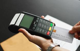 een vrouw die een hand-creditcard-veegmachine gebruikt om producten in de winkel te verkopen. concept van uitgaven via creditcard. foto