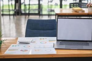 marketing, financieel, boekhouding, planning, zakenvrouwen analyseren bedrijfsresultaten en winst met grafiekstatistieken. gebruik een laptop en een rekenmachine om het saldo van het bedrijf te berekenen. foto