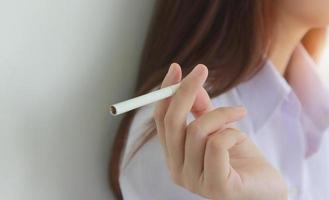 close-up van een jonge vrouw die een sigaret in haar hand houdt om te roken. foto