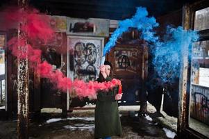 jong meisje met blauw en rood gekleurde rookbom in handen. foto