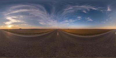 volledig bolvormig naadloos panorama 360 graden hoekzicht op asfaltweg zonder verkeer tussen velden in de avond voor zonsondergang met bewolkte hemel. 360 panorama in equirectangular projectie, vr ar inhoud foto