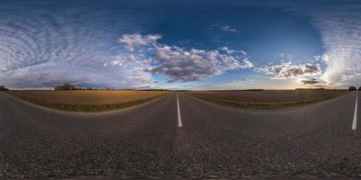 volledig bolvormig naadloos panorama 360 graden hoekzicht op asfaltweg zonder verkeer tussen velden in de avond voor zonsondergang met bewolkte hemel. 360 panorama in equirectangular projectie, vr ar inhoud foto