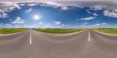 volledig bolvormig naadloos panorama 360 graden hoekzicht op asfaltweg zonder verkeer tussen velden met bewolkte lucht in equirectangular projectie, vr ar-inhoud foto