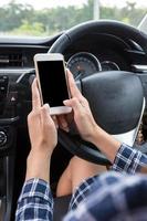 jonge vrouwelijke bestuurder met behulp van touchscreen smartphone in een auto. foto