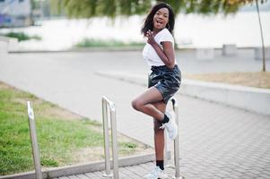 Afro-Amerikaanse donkere huid slank model poseerde in een zwarte leren korte broek en wit t-shirt. foto