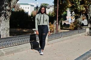 stadsportret van een positieve jonge vrouw met een donkere huid die een groene hoody en een bril draagt. foto