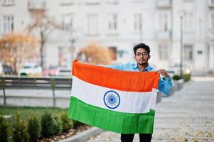 Zuid-Aziatische Indiase mannelijke student met de vlag van india buiten geposeerd. foto