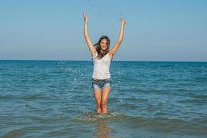 jong meisje spettert het water in de zee foto