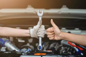 close-up klusjesman hand en deskundige monteur hand met een positief gebaar auto-onderhoudstool. het werk afmaken. auto reparatie dienstverleningsconcept. Onderhoudstechnieker foto