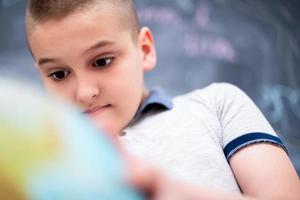 jongen die aardbol voor schoolbord gebruikt foto