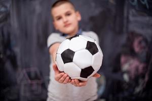 gelukkige jongen die een voetbal voor schoolbord houdt foto