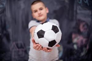 gelukkige jongen die een voetbal voor schoolbord houdt foto