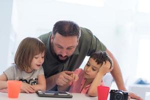 alleenstaande vader thuis met twee kinderen die spelletjes spelen op tablet foto