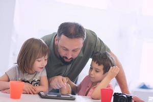 alleenstaande vader thuis met twee kinderen die spelletjes spelen op tablet foto