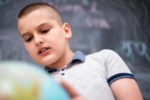 jongen die aardbol voor schoolbord gebruikt foto