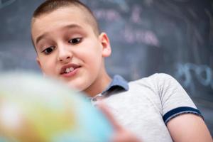 jongen die aardbol voor schoolbord gebruikt foto