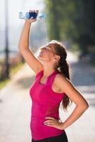 vrouw die water uit de fles op haar hoofd giet foto