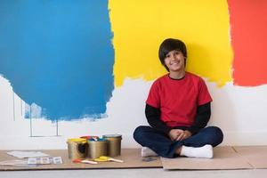 jonge jongensschilder rust na het schilderen van de muur foto