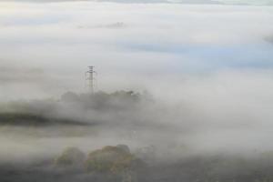 elektrische hoogspanningslijnen en pylonen die uit de mist komen foto