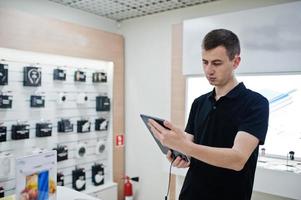 verkoper man mobiele telefoon professionele adviseur in tech winkel of winkel houden nieuwe tablet. foto