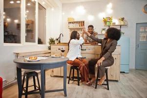 drie Afro-Amerikaanse vrienden die tijd doorbrengen in de keuken met wijn. zwarte mensen die thuis ontspannen. foto