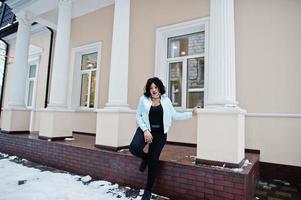 stijlvolle Afro-Amerikaanse plus size model in de straten van de stad op winterdag. foto