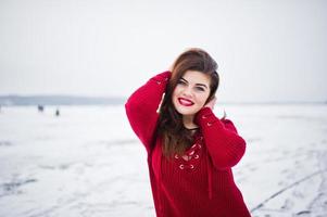 brunette plus size model op rood tegen bevroren meer op winterdag. foto