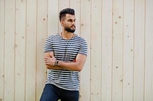 knappe lange Arabische baard man model op gestript shirt buiten tegen houten achtergrond gesteld. modieuze Arabische man. foto