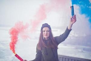 jong meisje met blauw en rood gekleurde rookbom in handen. foto