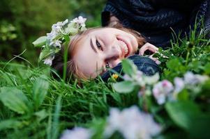 jonge brunette meisje liggend op groen gras met takken van bloesem boom. foto