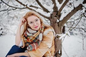 portret van blond meisje in glazen, rode bontjas en sjaal op winterdag. foto