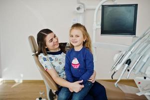 babymeisje bij tandartsstoel met haar arts. kinderen tandheelkundige. foto