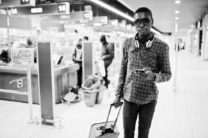 Afro-Amerikaanse man in geruit overhemd met koffer en rugzak. zwarte man tegen kassier supermarkt. foto