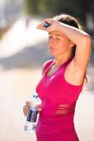 vrouw drinkt water uit een fles na het joggen foto