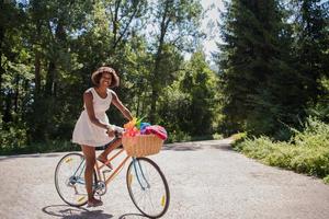 mooie jonge Afro-Amerikaanse vrouw fietsen in het bos foto