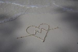 harten getekend op het zand van een strand foto