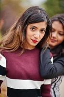 portret van twee jonge mooie Indiase of Zuid-Aziatische tienermeisjes in jurk in de buurt van struiken. foto